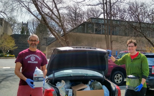 Two men stand in front of an open car trunk